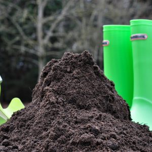 lawnscape soil next to green wellies and garden tool