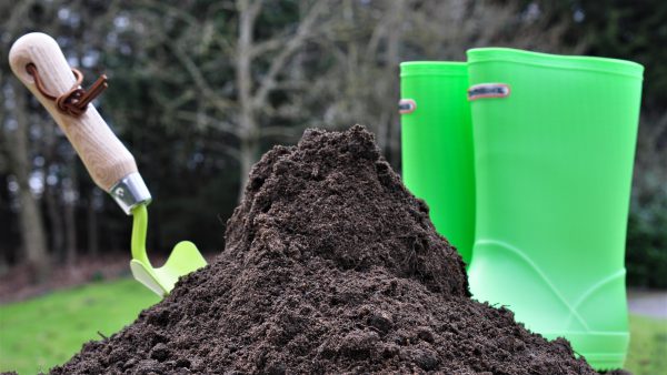 lawnscape soil next to green wellies and garden tool